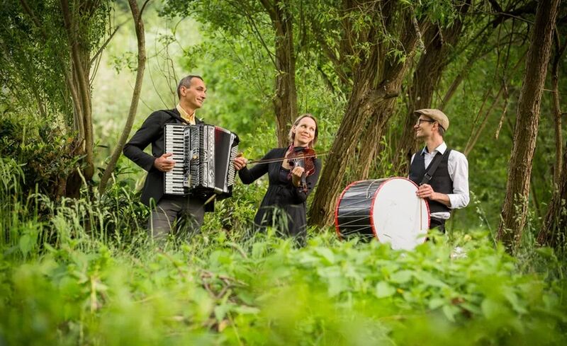 Die drei Musiker von Zakuska mit ihren Instrumenten in grünem Wald