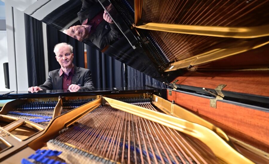 Der Pianist Kolja Lessing sitzt an einem aufgeklappten Flügel