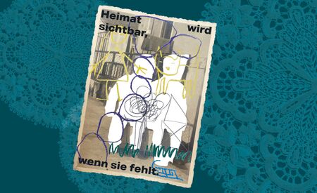 Ein Plakat mit dem Schriftzug "Heimat wird sichtbar, wenn sie fehlt" zeigt ein altes Schwarz-Weiß-Foto, es liegt auf einer Spitzendecke