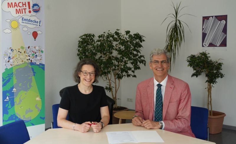 Dr. Christine Absmeier, Leiterin des Hauses der Heimat des Landes Baden-Württemberg, und René Wollnitz, Schulleiter des Königin-Olga-Stifts, unterzeichnen den Kooperationsvertrag.