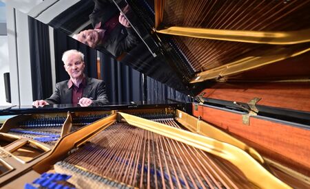 Der Pianist Kolja Lessing sitzt an einem aufgeklappten Flügel