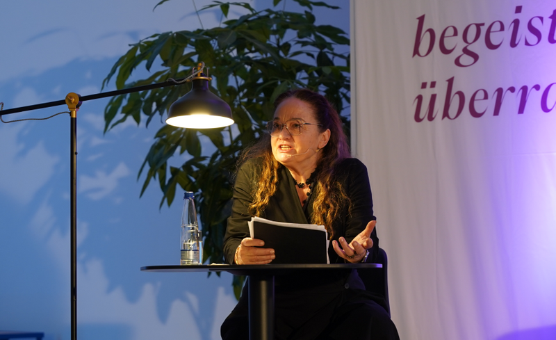 Barbara Stoll während einer Lesung an einem Bistrotisch sitzend
